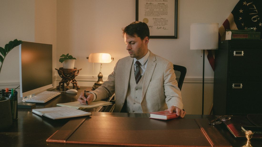 Thomas Plan writing at his desk in the office.