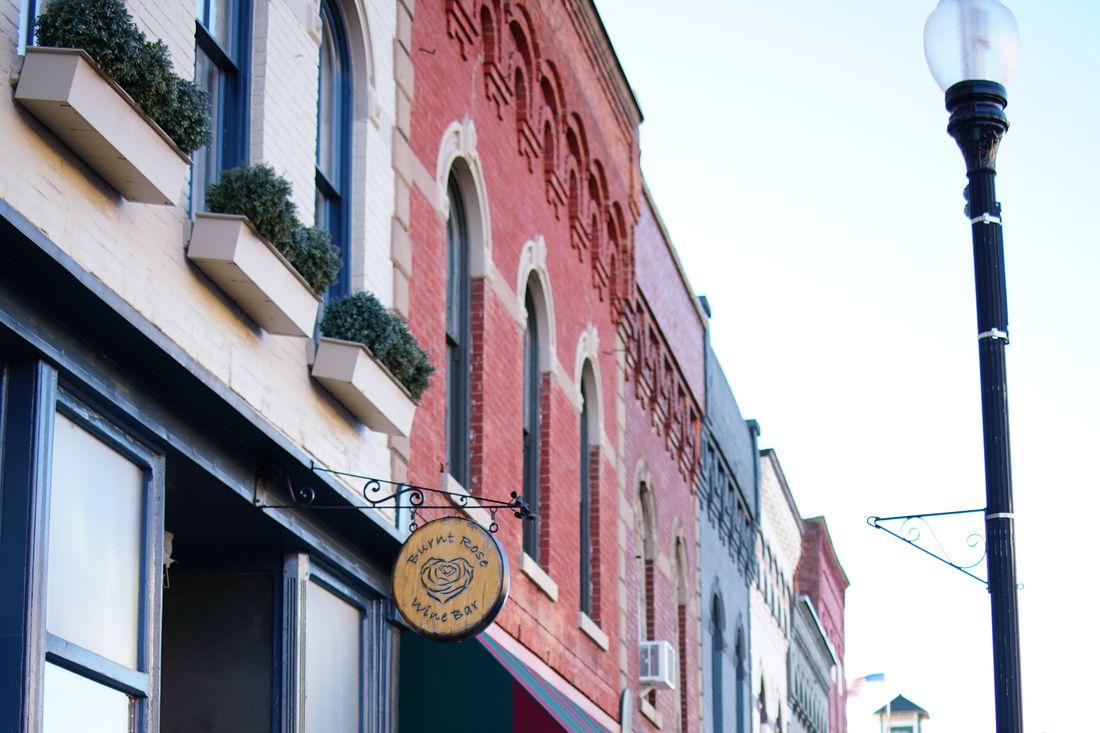 Brick shopfronts with arched windows, flower boxes and a cast-iron street lamp on Main Street in Penn Yan.